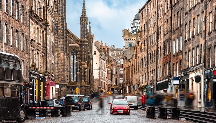 Cobbled street of Lawnmarket in Edinburgh with historic buildings and tourists exploring.