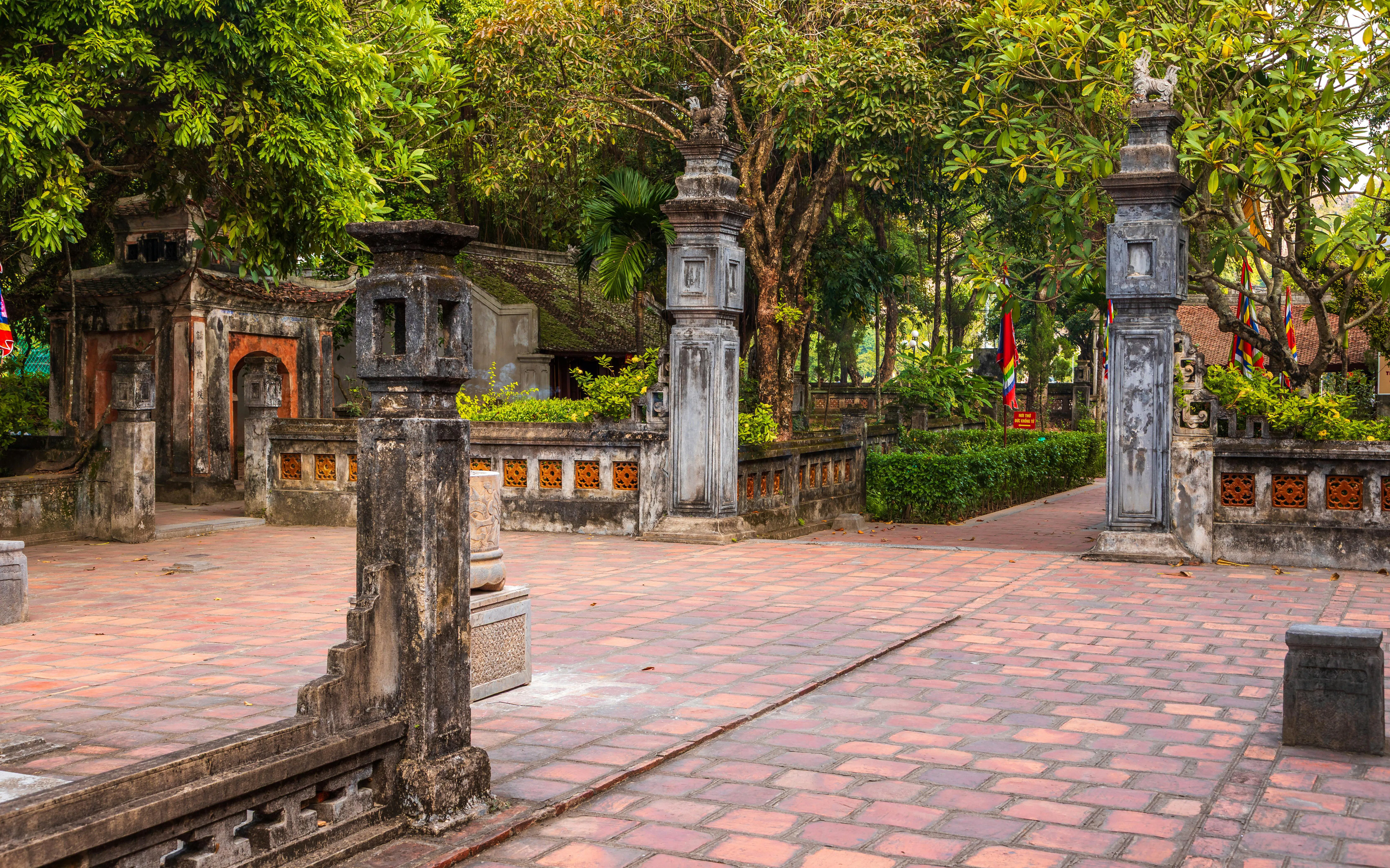 Ancient temple courtyard with stone pillars and greenery in Hoa Lu, Vietnam.