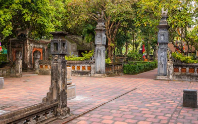 Ancient temple courtyard with stone pillars and greenery in Hoa Lu, Vietnam.