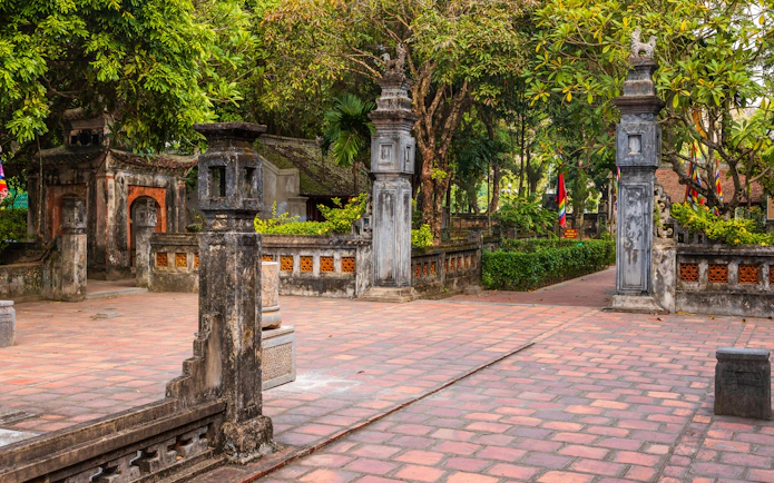 Ancient temple courtyard with stone pillars and greenery in Hoa Lu, Vietnam.