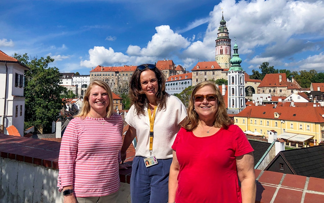 Tour guide with tourists in Cesky Krumlov, castle and town view in background.