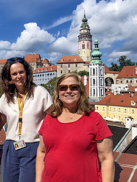 Tour guide with tourists in Cesky Krumlov, castle and town view in background.