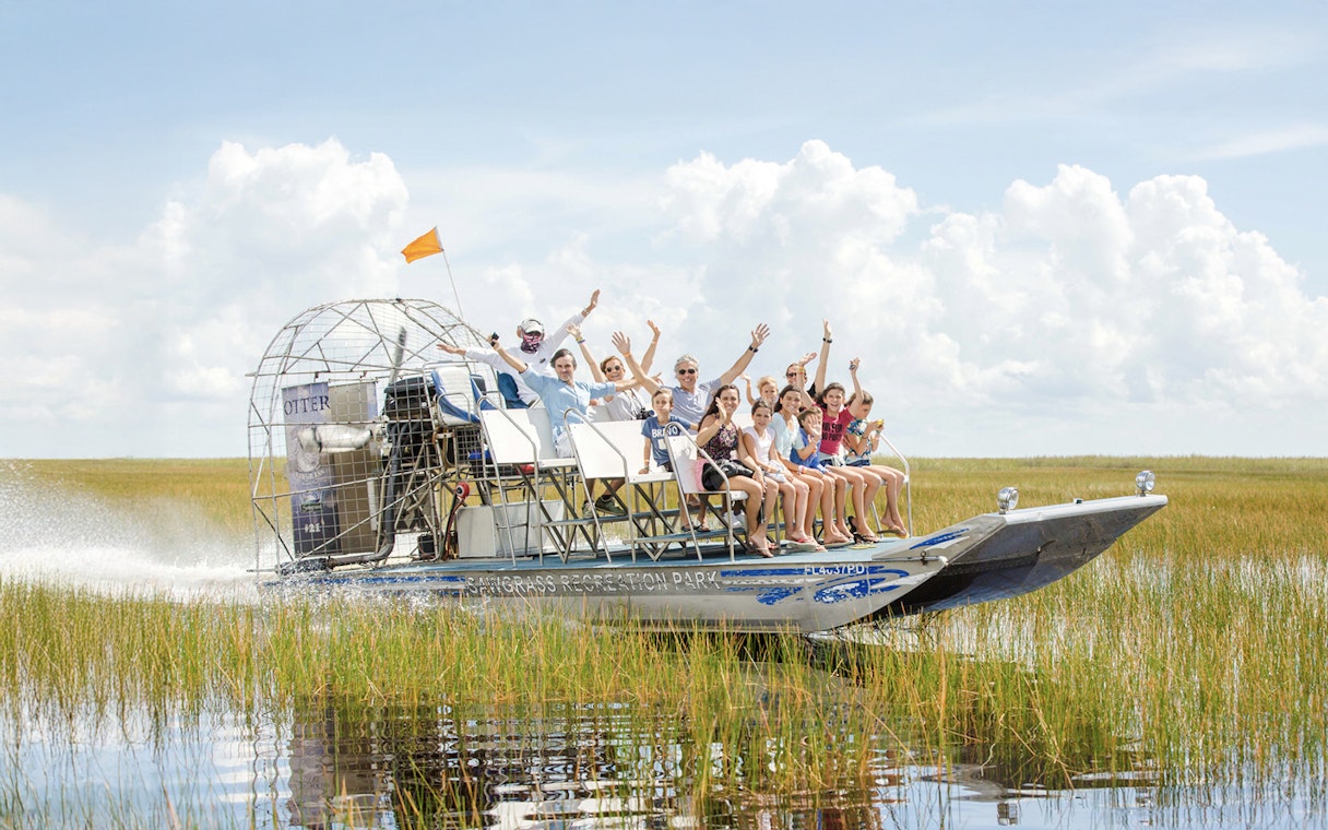 Group enjoying an Everglades private airboat tour through marshlands.