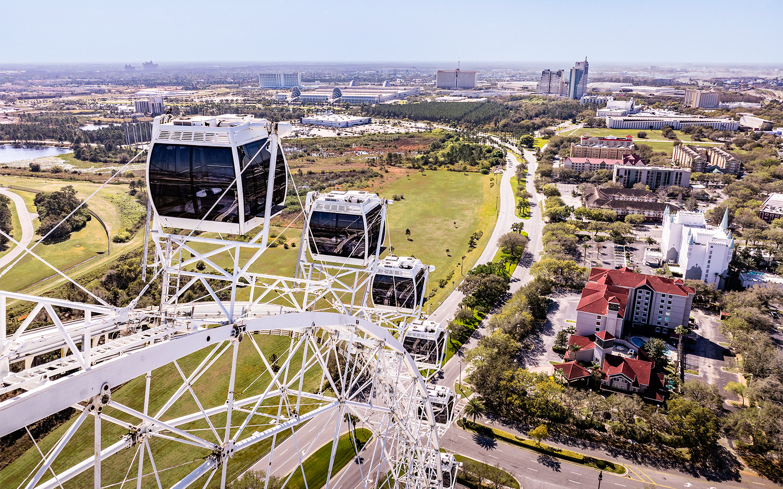 Ferris wheel cabins at ICON Park, Orlando with cityscape and greenery in the background.