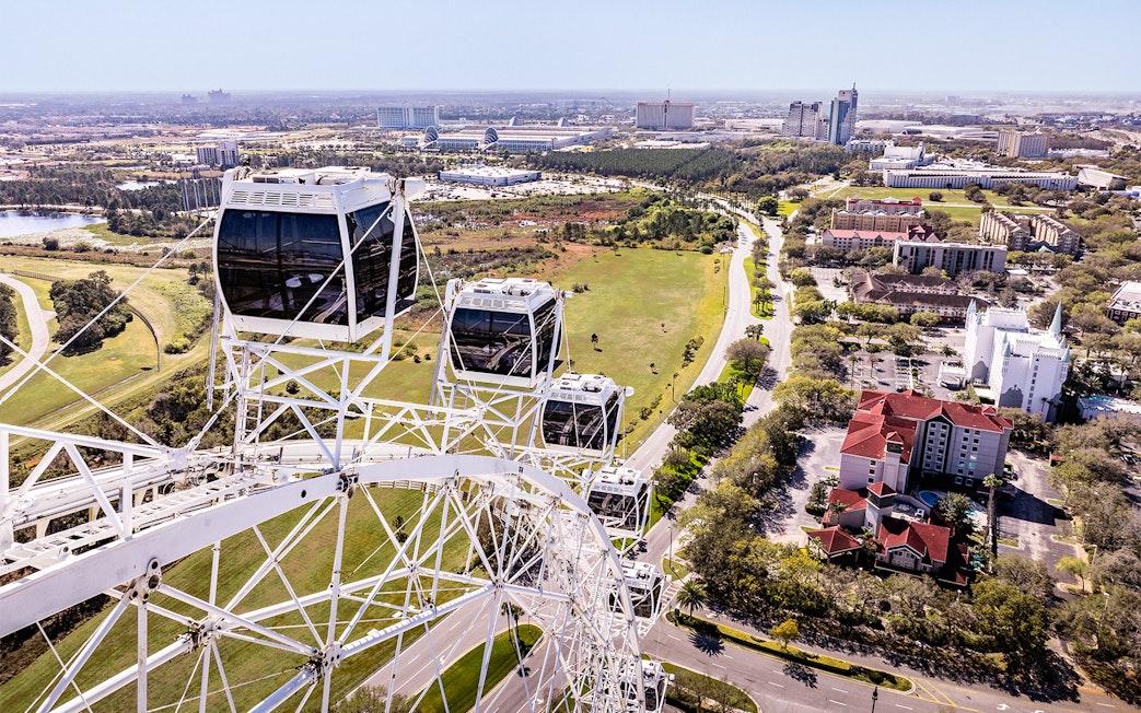 Ferris wheel cabins at ICON Park, Orlando with cityscape and greenery in the background.