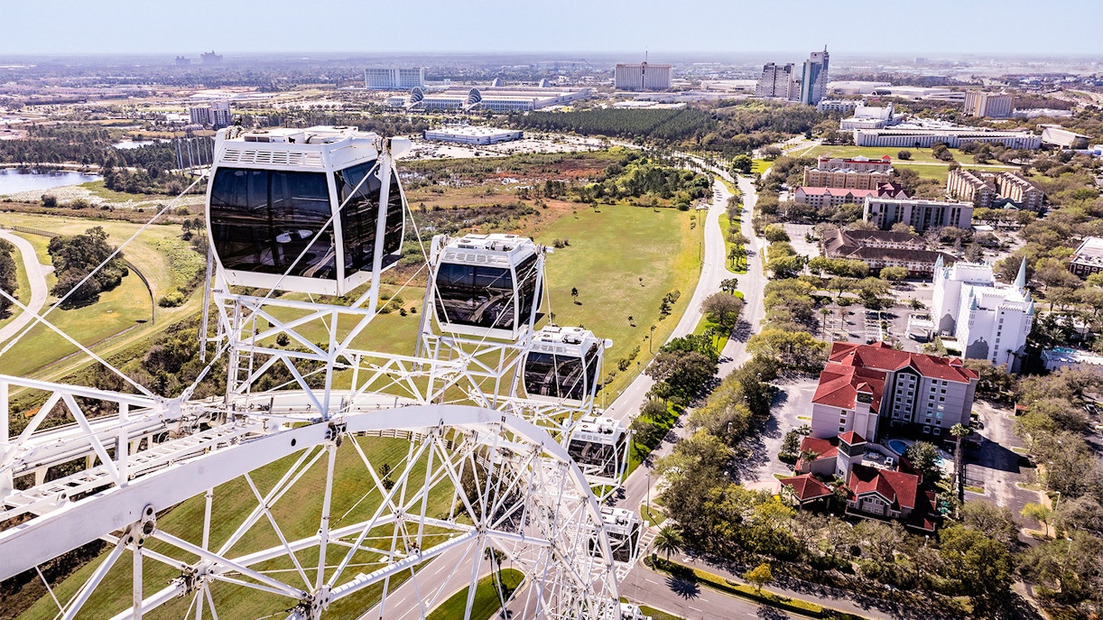 Ferris wheel cabins at ICON Park, Orlando with cityscape and greenery in the background.
