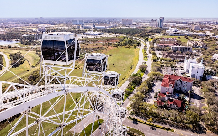 Ferris wheel cabins at ICON Park, Orlando with cityscape and greenery in the background.