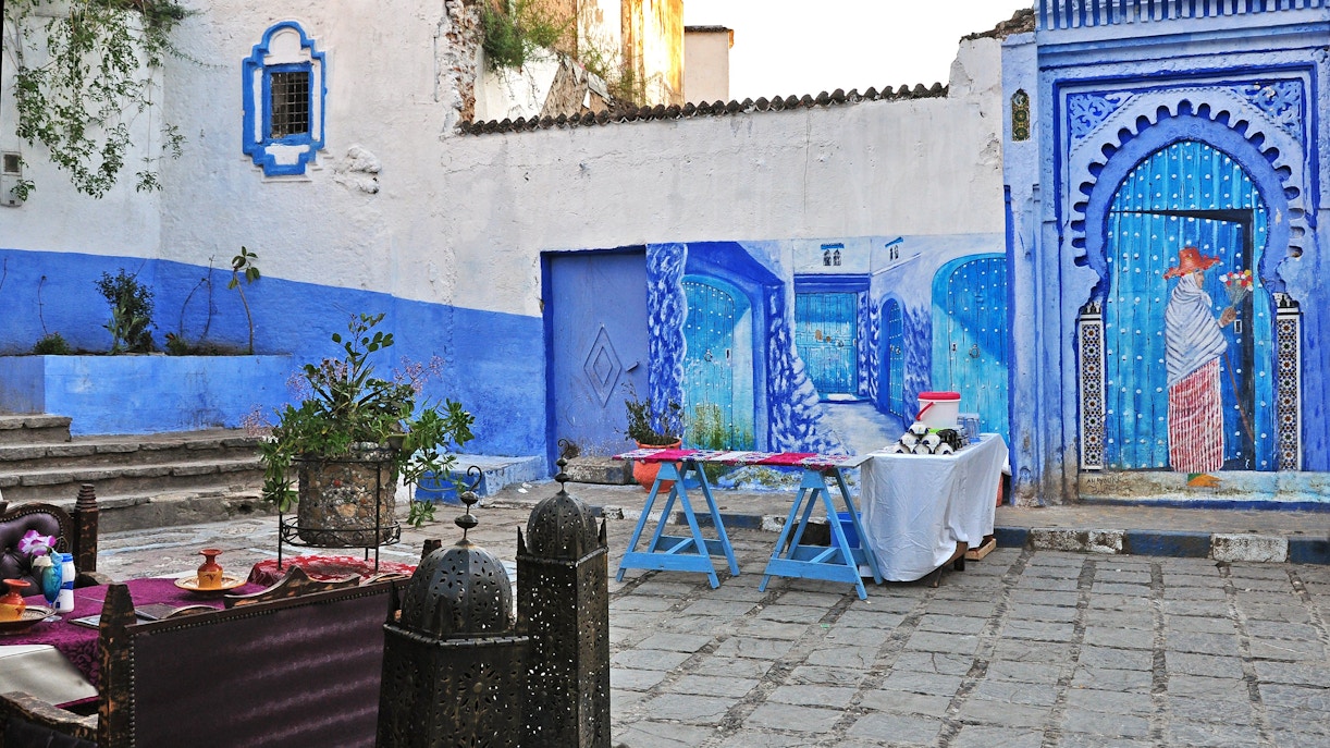 Outdoor restaurant in Chefchaouen with blue wall paintings and decorative lanterns, Morocco.
