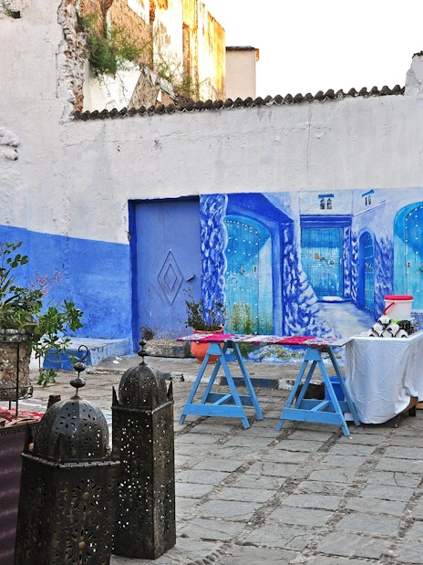 Outdoor restaurant in Chefchaouen with blue wall paintings and decorative lanterns, Morocco.