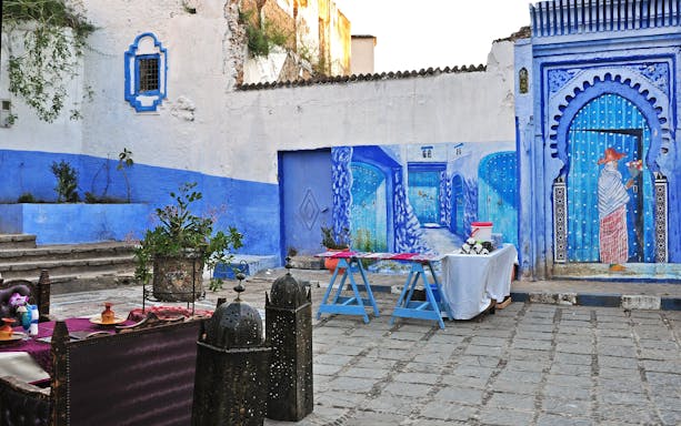 Outdoor restaurant in Chefchaouen with blue wall paintings and decorative lanterns, Morocco.