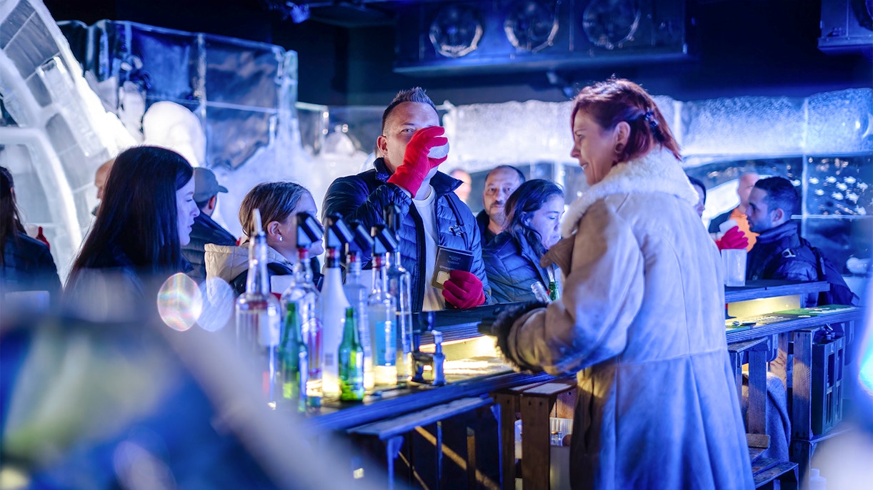 Bartender pouring drinks at Berlin Icebar with ice sculptures in the background.