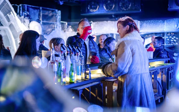 Bartender pouring drinks at Berlin Icebar with ice sculptures in the background.