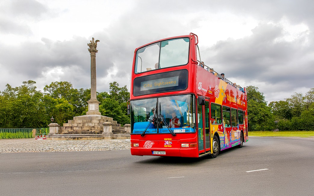Double-decker bus on Dublin street near a monument, part of City Sightseeing Hop-On-Hop-Off Tour.
