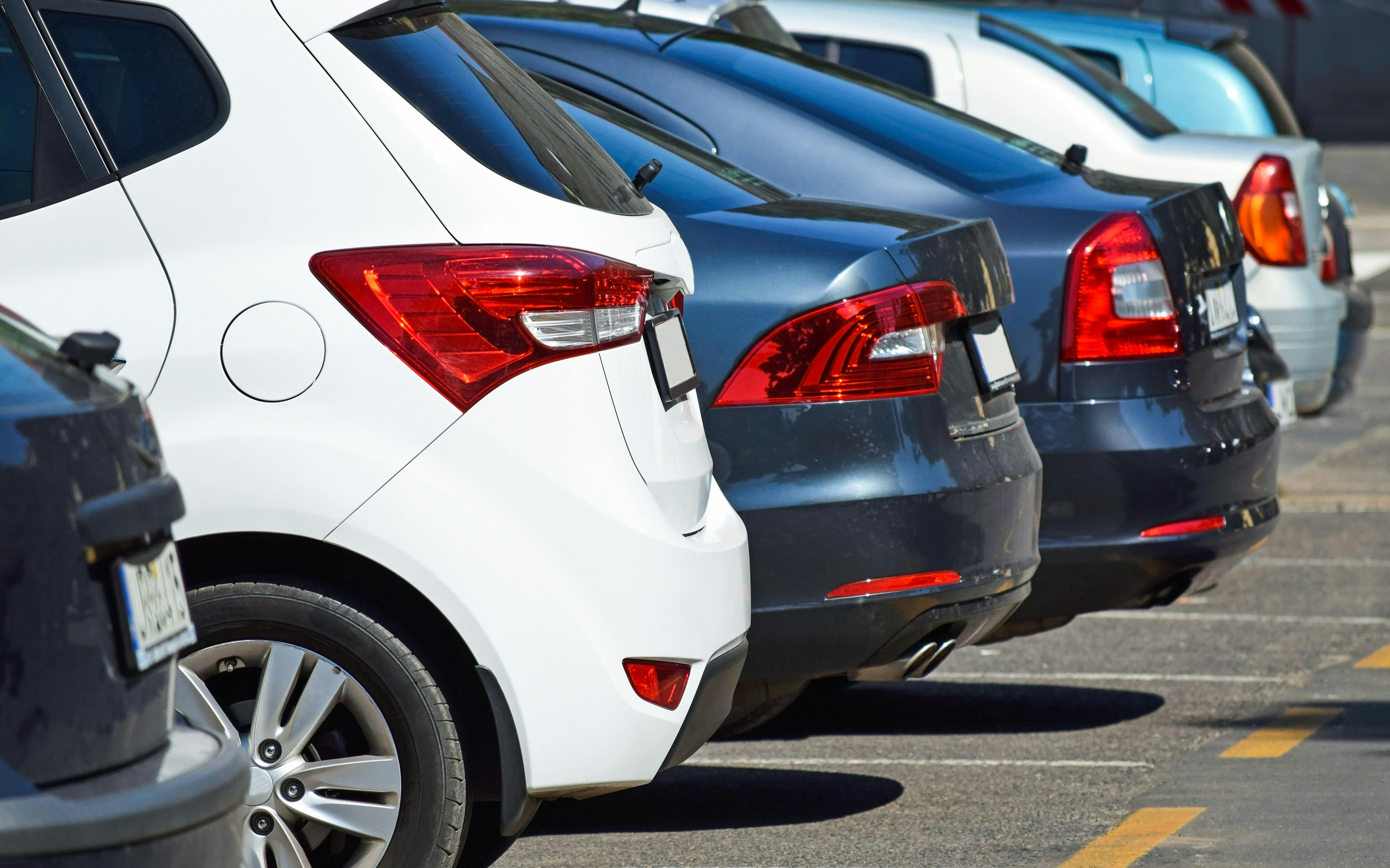 Cars parked in a row in a sunny parking lot.