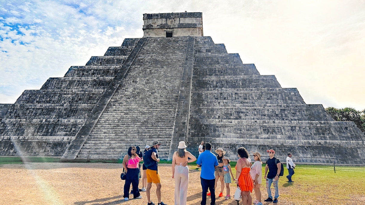 Tourist guide explaining Chichen Itza temple history to visitors in Mexico.