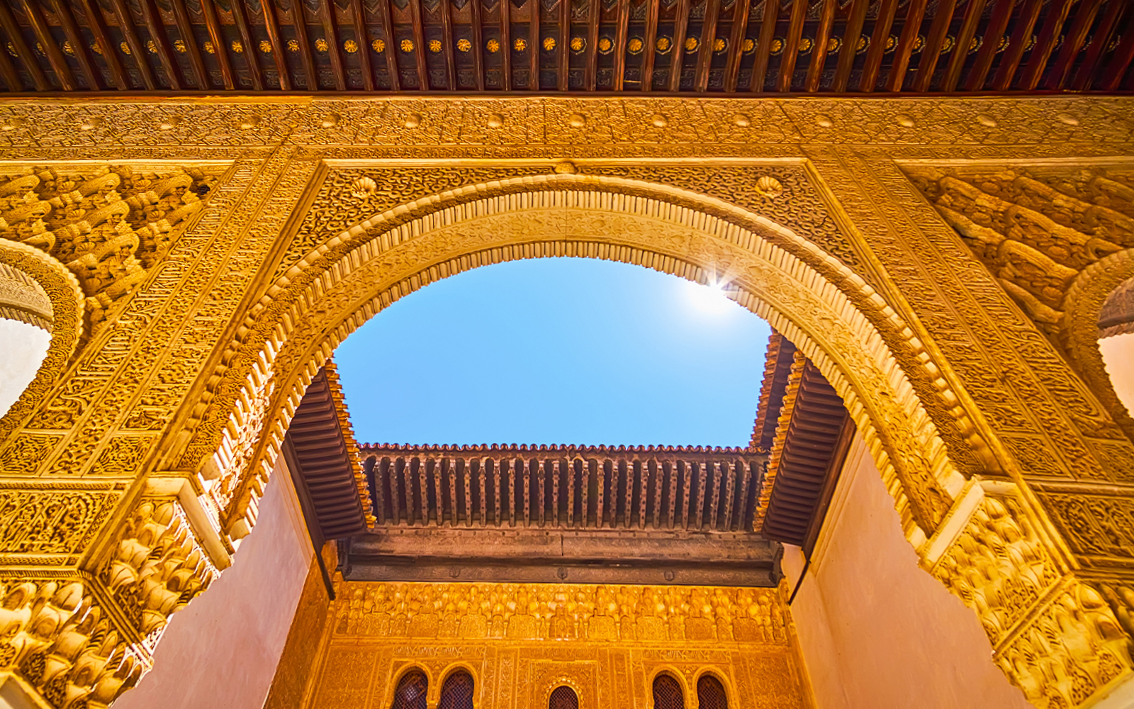 Ornate archway detail in Alhambra, Granada, Spain, under a clear blue sky.