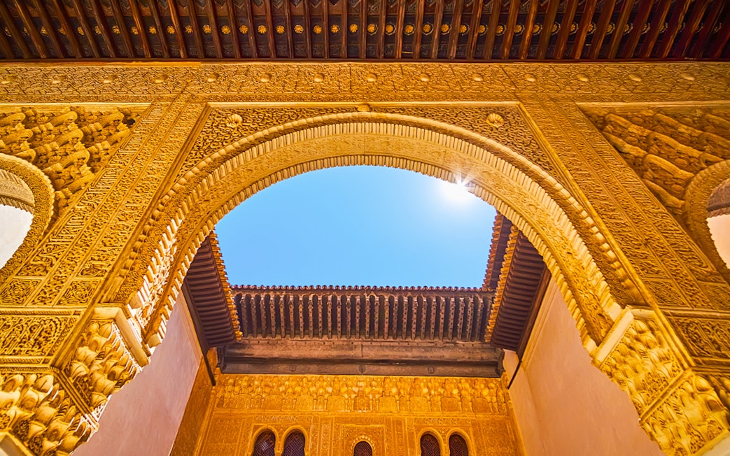 Ornate archway detail in Alhambra, Granada, Spain, under a clear blue sky.