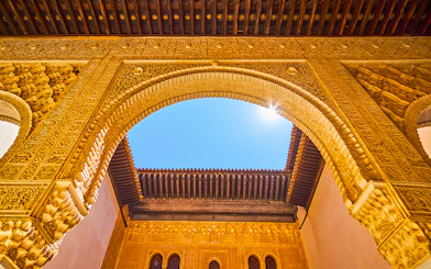 Ornate archway detail in Alhambra, Granada, Spain, under a clear blue sky.