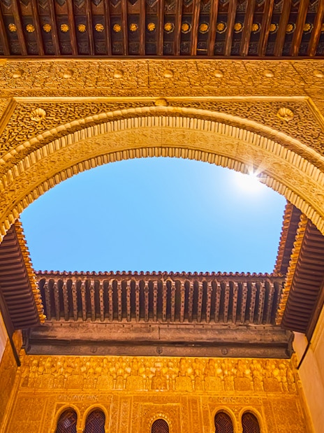Ornate archway detail in Alhambra, Granada, Spain, under a clear blue sky.