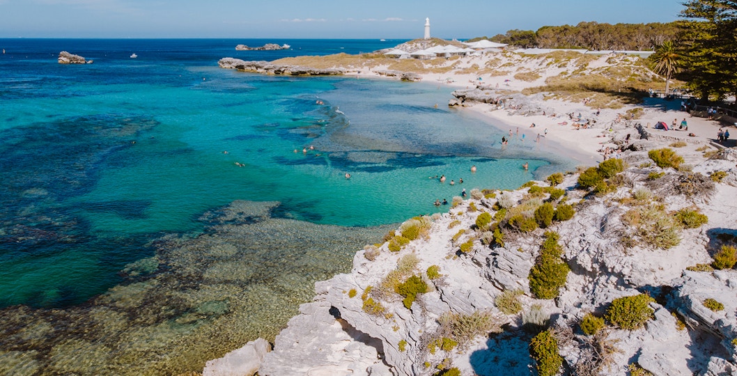 Tourists on Segways exploring Rottnest Island with ferry in background from Perth or Fremantle.