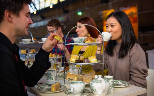 Guests enjoying afternoon tea at Cutty Sark with pastries and tea sets.