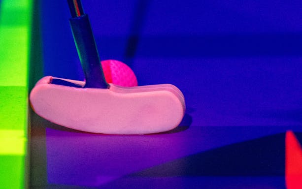 Putter and ball on 3D blacklight minigolf course in Dubai.