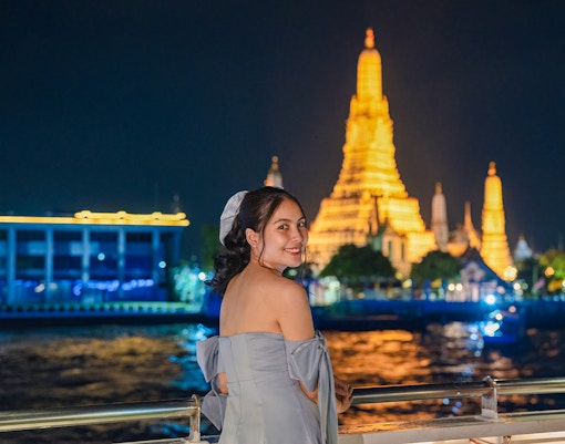 Cruise on Chao Phraya River with Wat Arun illuminated at night in Bangkok.