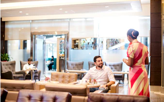 VIP lounge at Dubai International Airport with guests and staff interaction.