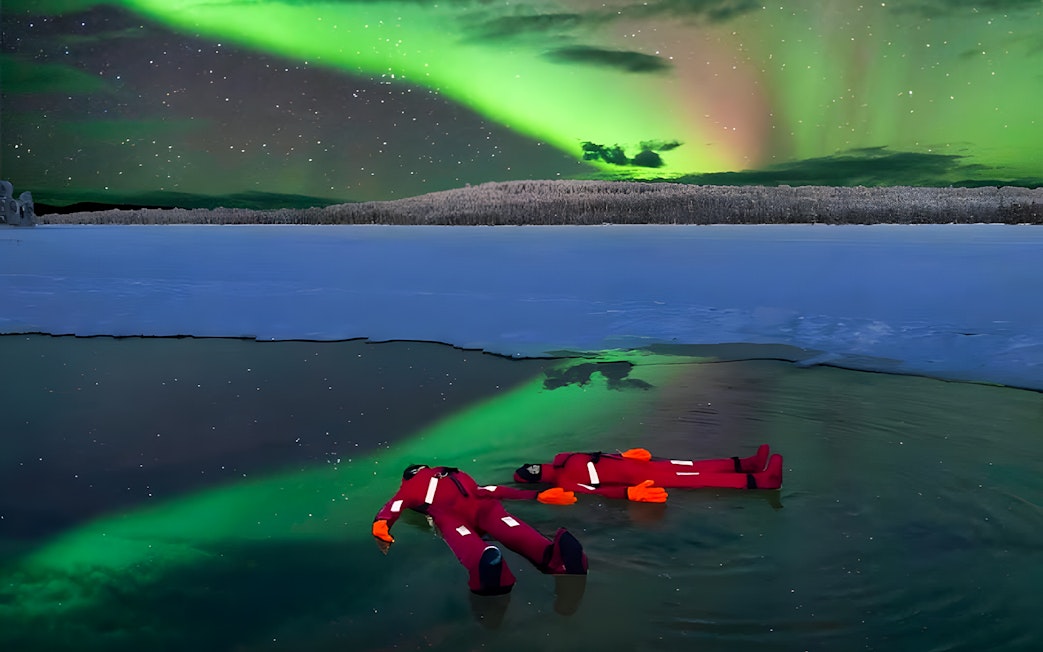 Person ice floating under Northern Lights in Rovaniemi.