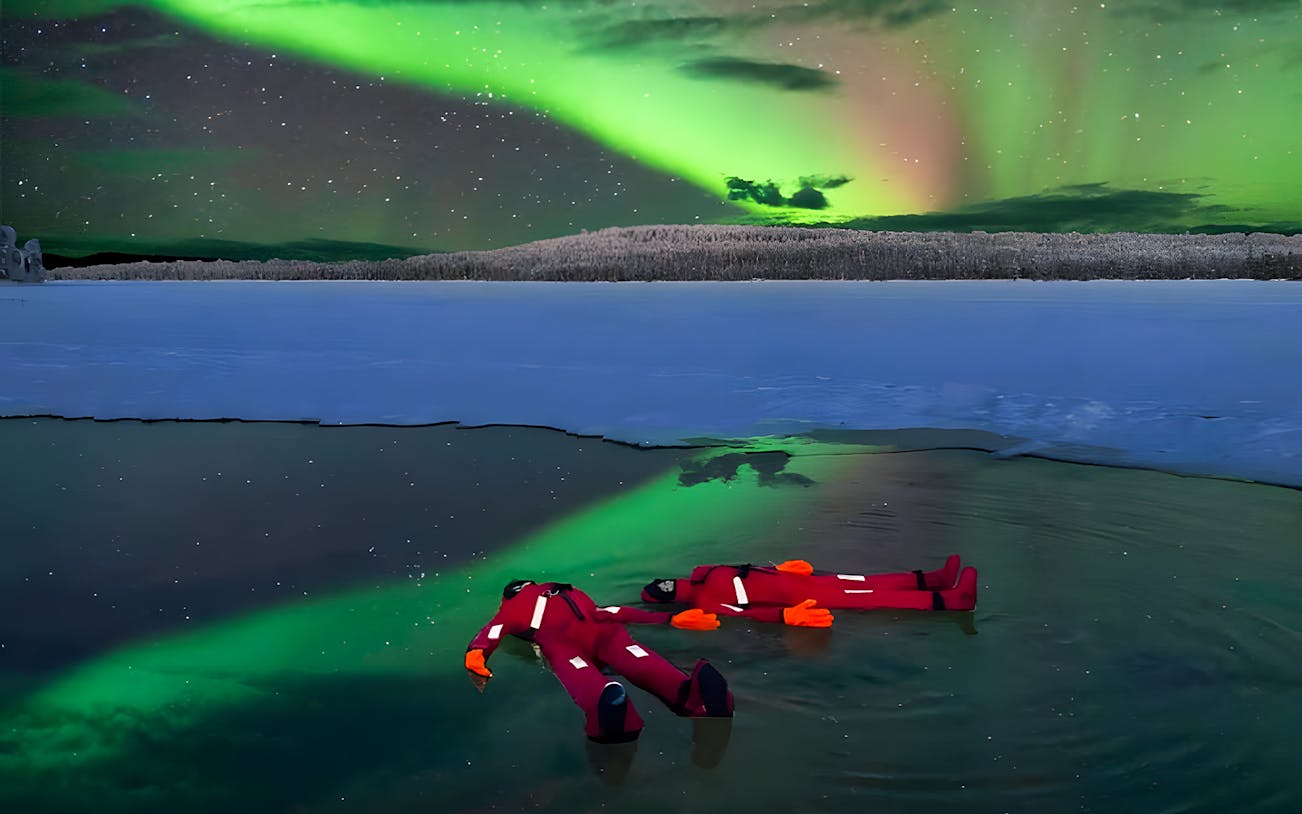 Person ice floating under Northern Lights in Rovaniemi.