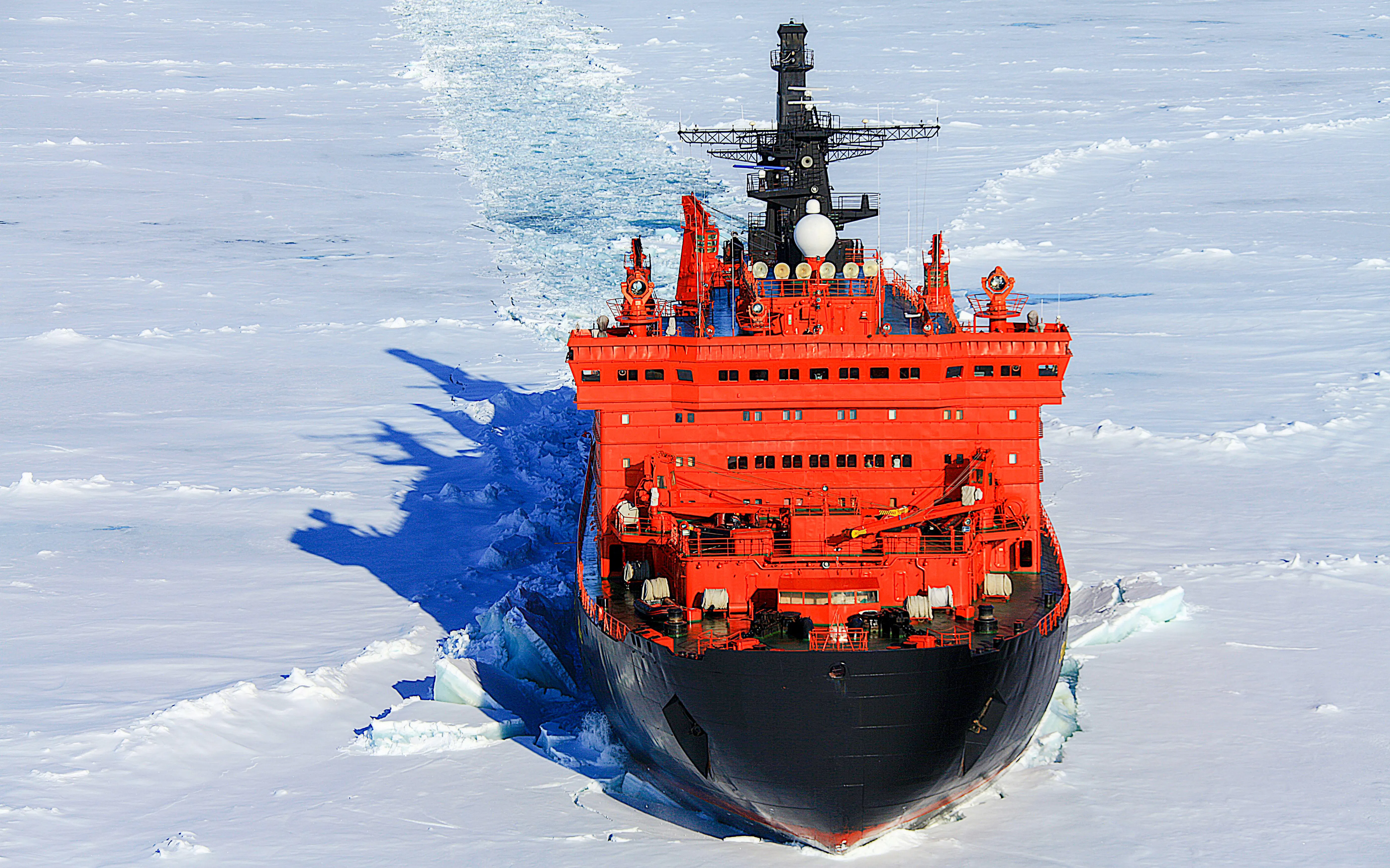 Red icebreaker ship navigating through Arctic Ocean ice.