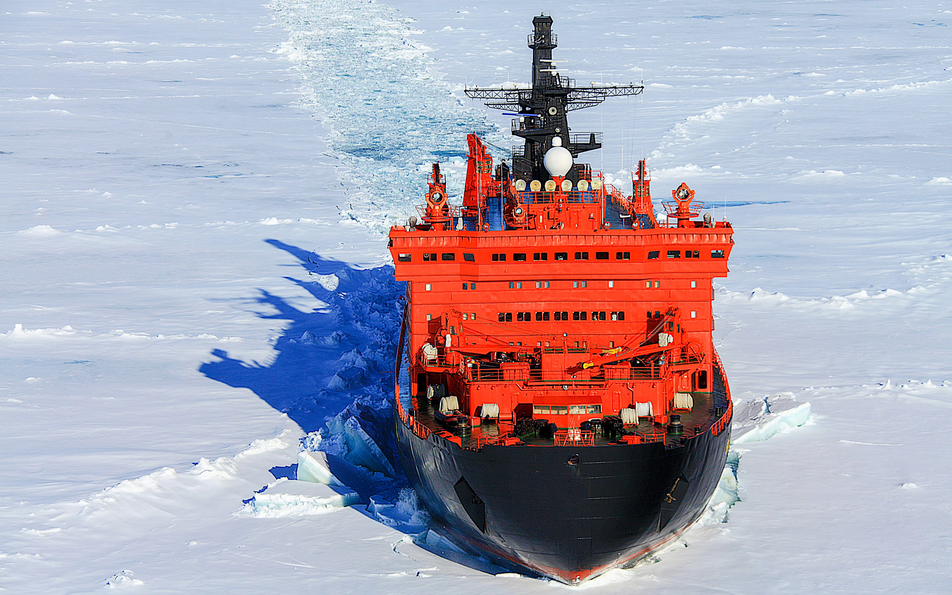 Red icebreaker ship navigating through Arctic Ocean ice.