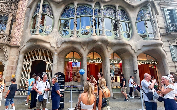 Casa Batlló entrance with visitors in Barcelona, showcasing Gaudí's unique architecture.