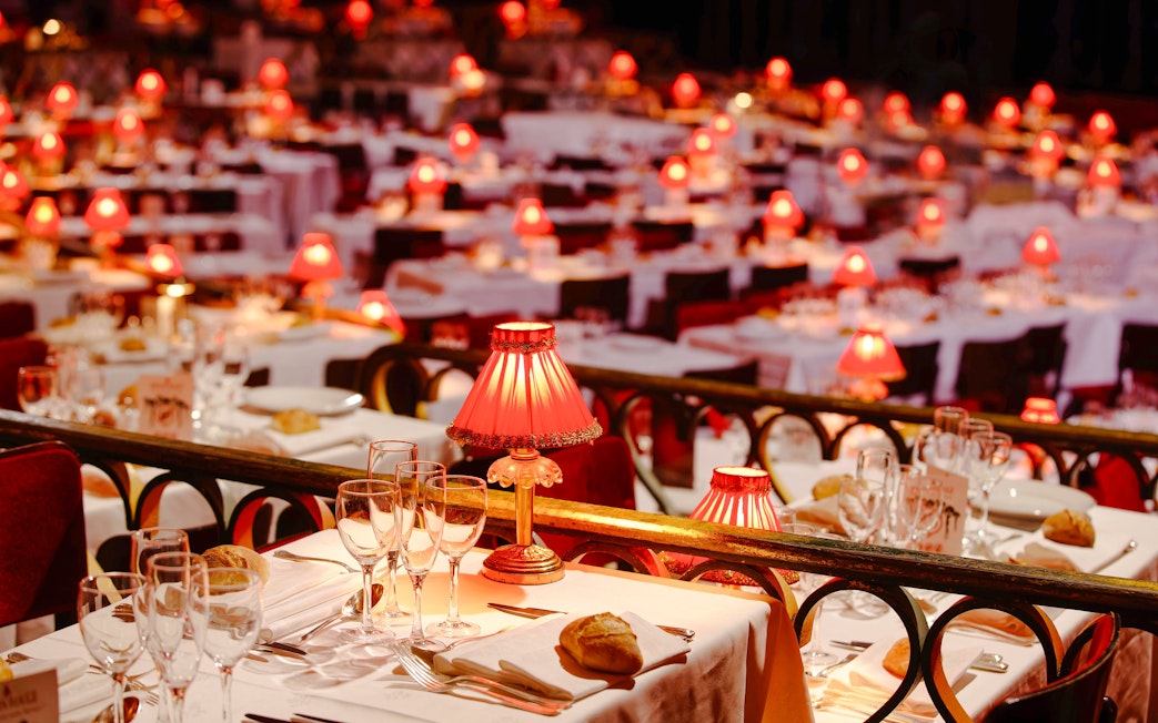 Elegant dining setup with red lamps at Moulin Rouge Show, Paris.