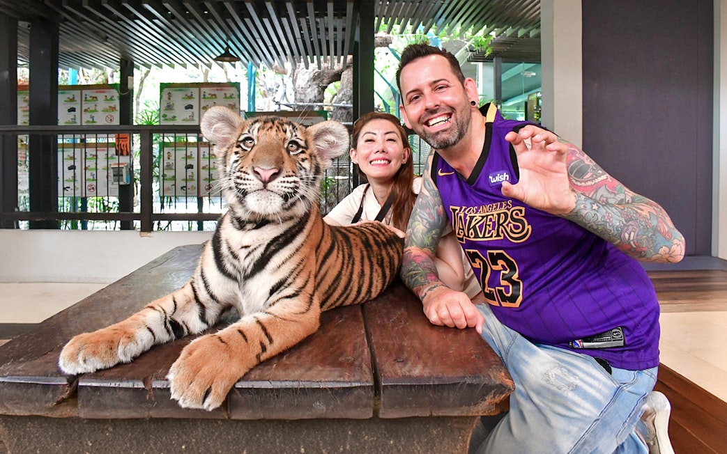 Visitors posing with a tiger cub at Tiger Park Pattaya.