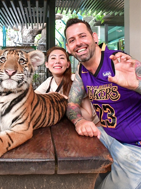 Visitors posing with a tiger cub at Tiger Park Pattaya.