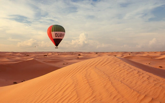 Hot air balloon over Dubai desert dunes during premium tour experience.