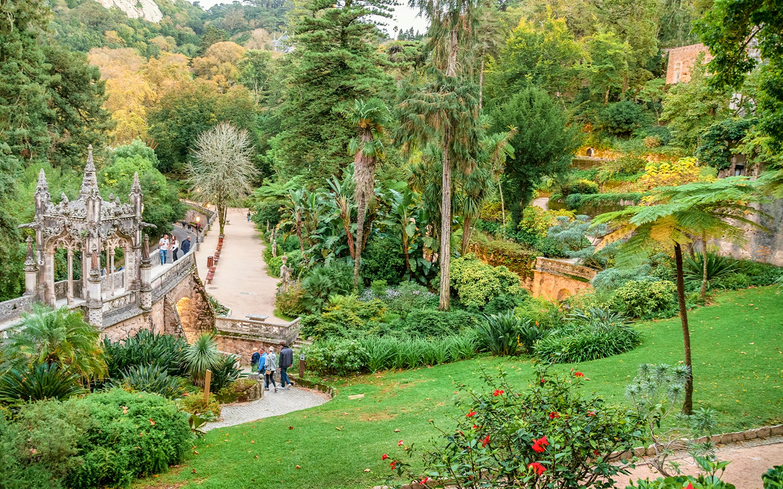Quinta da Regaleira garden with tourists exploring pathways and historic architecture in Sintra, Portugal.