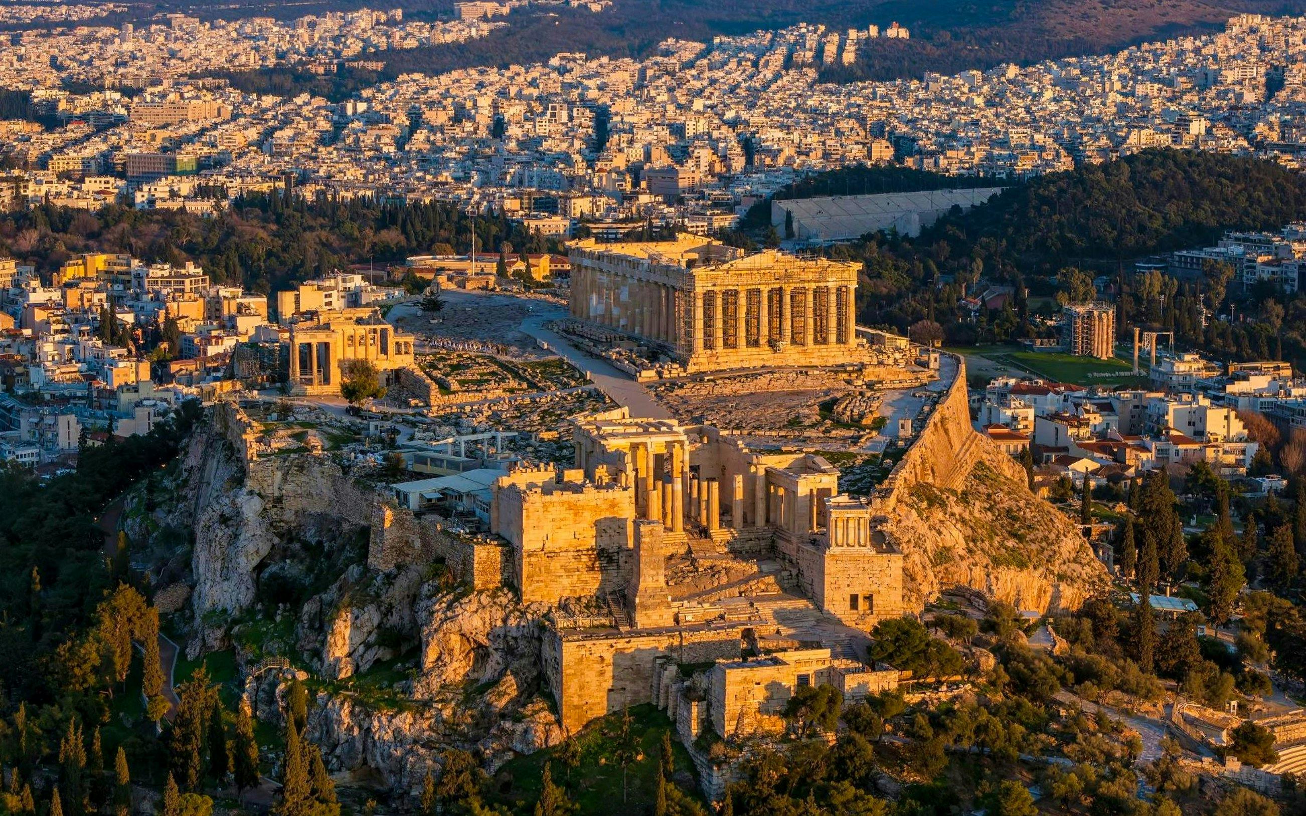 Acropolis and Parthenon at sunset, Athens cityscape in the background.