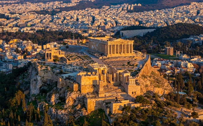 Acropolis and Parthenon at sunset, Athens cityscape in the background.