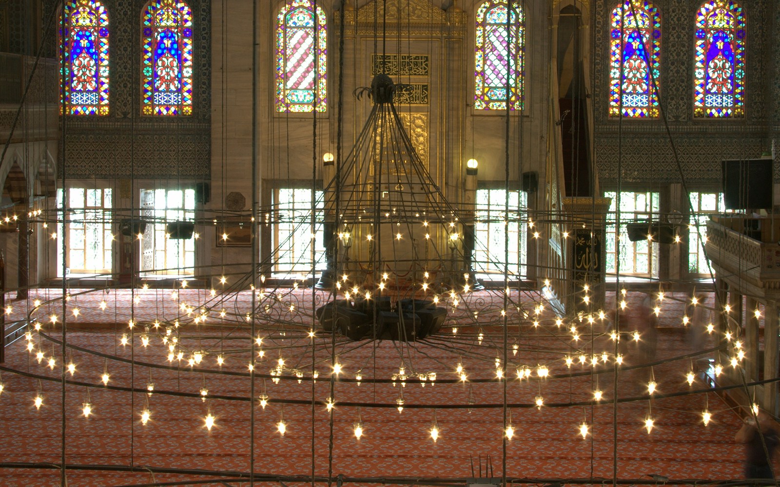 Prayer hall interior with chandeliers and stained glass in the Blue Mosque, Istanbul.