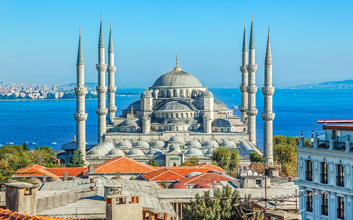 Blue Mosque exterior with minarets and domes, Istanbul skyline in background.