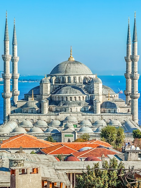 Blue Mosque exterior with minarets and domes, Istanbul skyline in background.