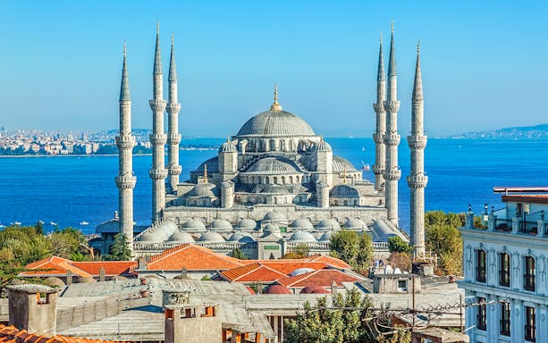 Blue Mosque exterior with minarets and domes, Istanbul skyline in background.