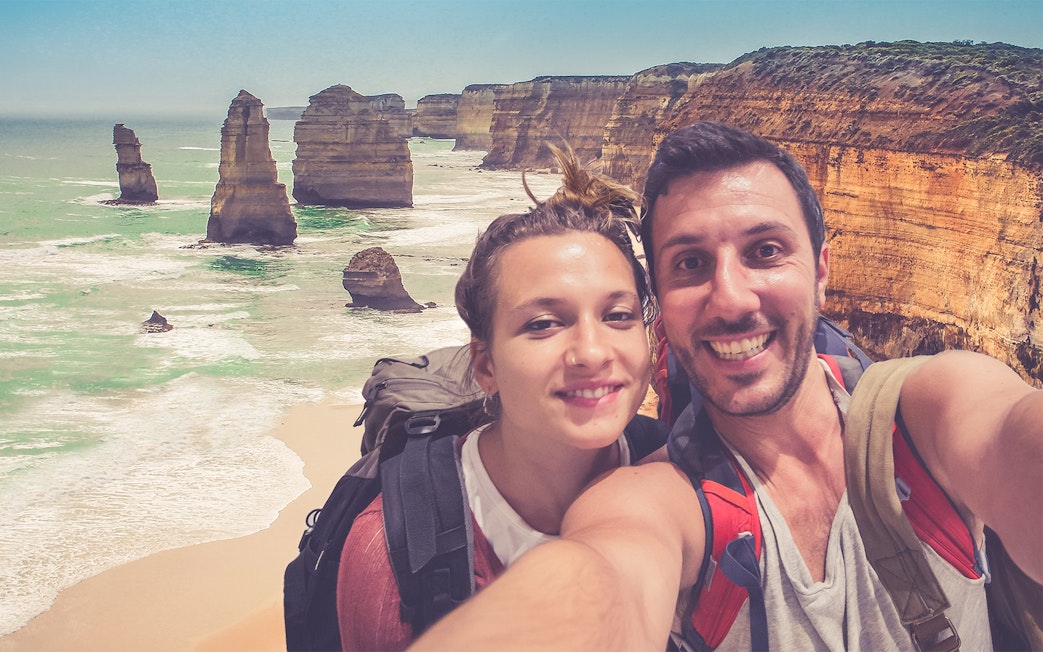 Couple taking a selfie with the 12 Apostles rock formations on the Great Ocean Road, Australia.