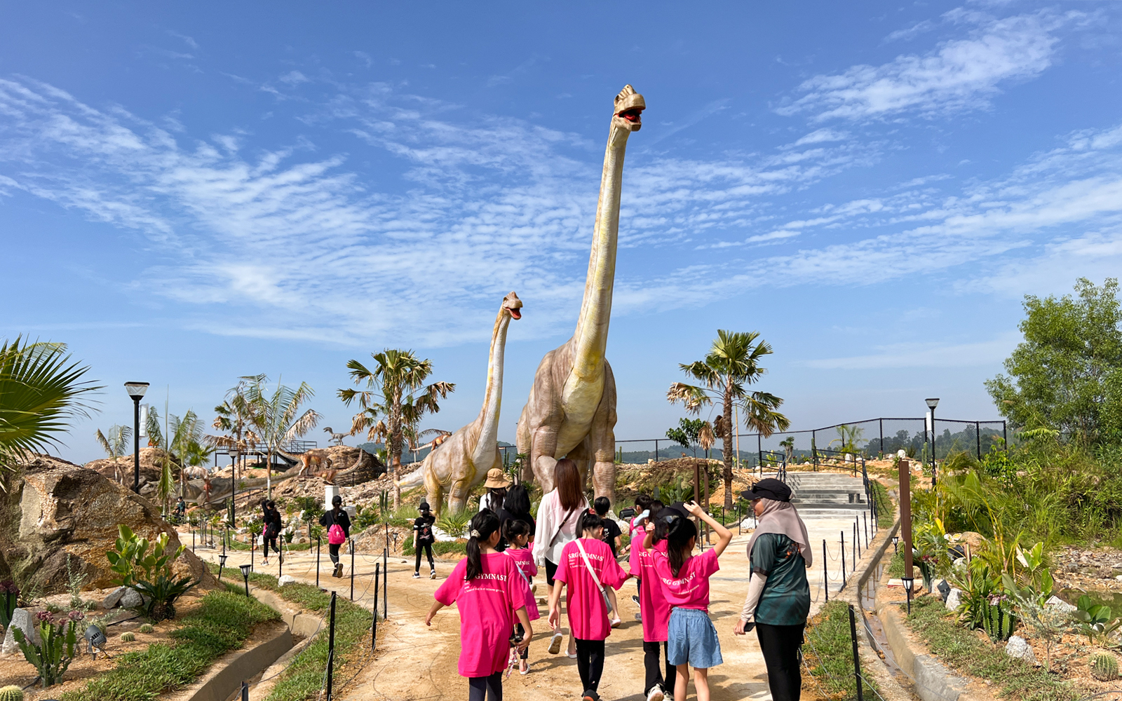 Visitors walking past dinosaur sculptures in Dino Desert attraction.