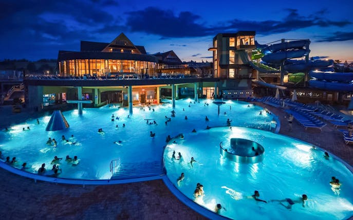 Zakopane Thermal Baths illuminated at night with steam rising from the warm water, Poland.