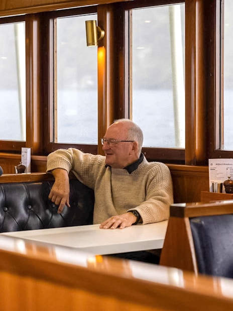 Passengers enjoying conversation in a cozy dining area on Doubtful Sound overnight cruise.
