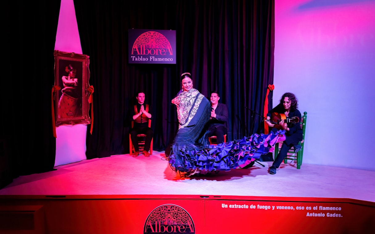 Flamenco dancer performing at La Alboreá Tablao Flamenco with musicians on stage.