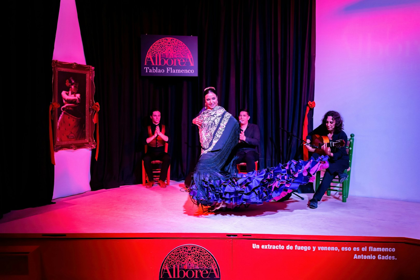 Flamenco dancer performing at La Alboreá Tablao Flamenco with musicians on stage.